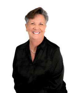 A professional headshot of a woman with short gray hair, wearing a black blouse and a small necklace. She is smiling and facing the camera against a plain white background.