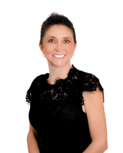 A professional headshot of a woman with dark hair pulled back, wearing a black lace top. She is smiling and facing the camera against a plain white background.