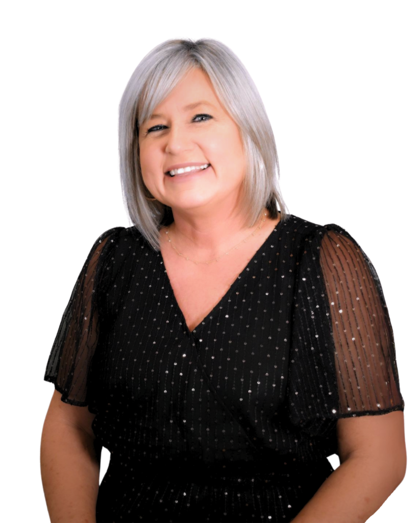 A professional headshot of a woman with short gray hair, wearing a black top with sheer sleeves and small dotted patterns. She is smiling and facing the camera against a plain white background.